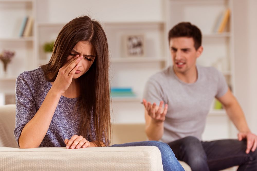 Woman crying with back turned to angry man
